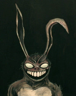 A dark rabbit with very long bent ears, blank pale eyes and a broad toothy grin faces forward.